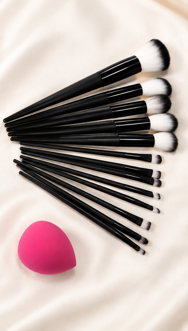 Makeup brush set fanned out on cream silk with pink blending sponge