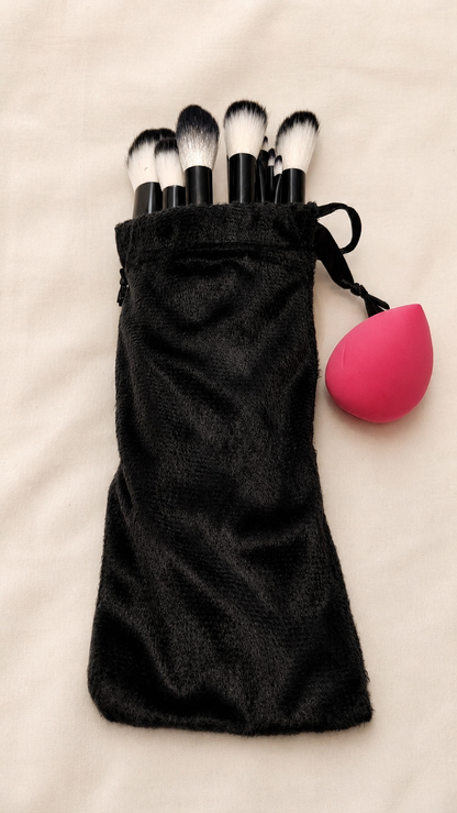 Black velvet pouch with makeup brushes and pink blending sponge